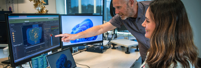 Two people looking at computer screen with graphs