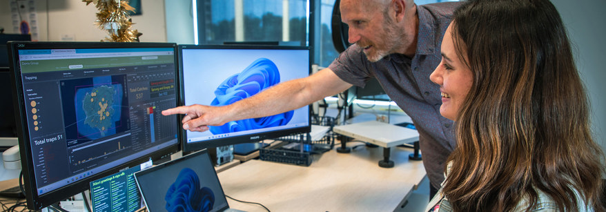 Two people looking at computer screen with graphs